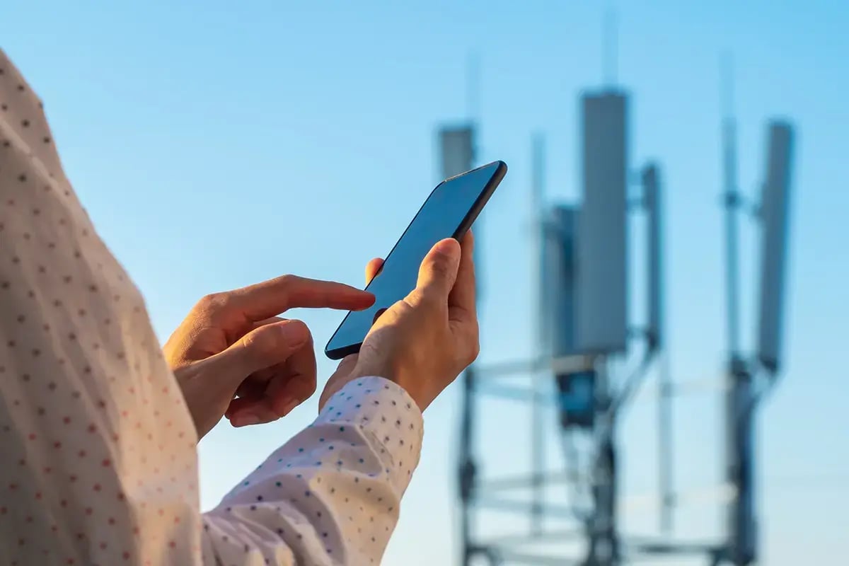 Man using a mobile phone with a telecom base station in the background