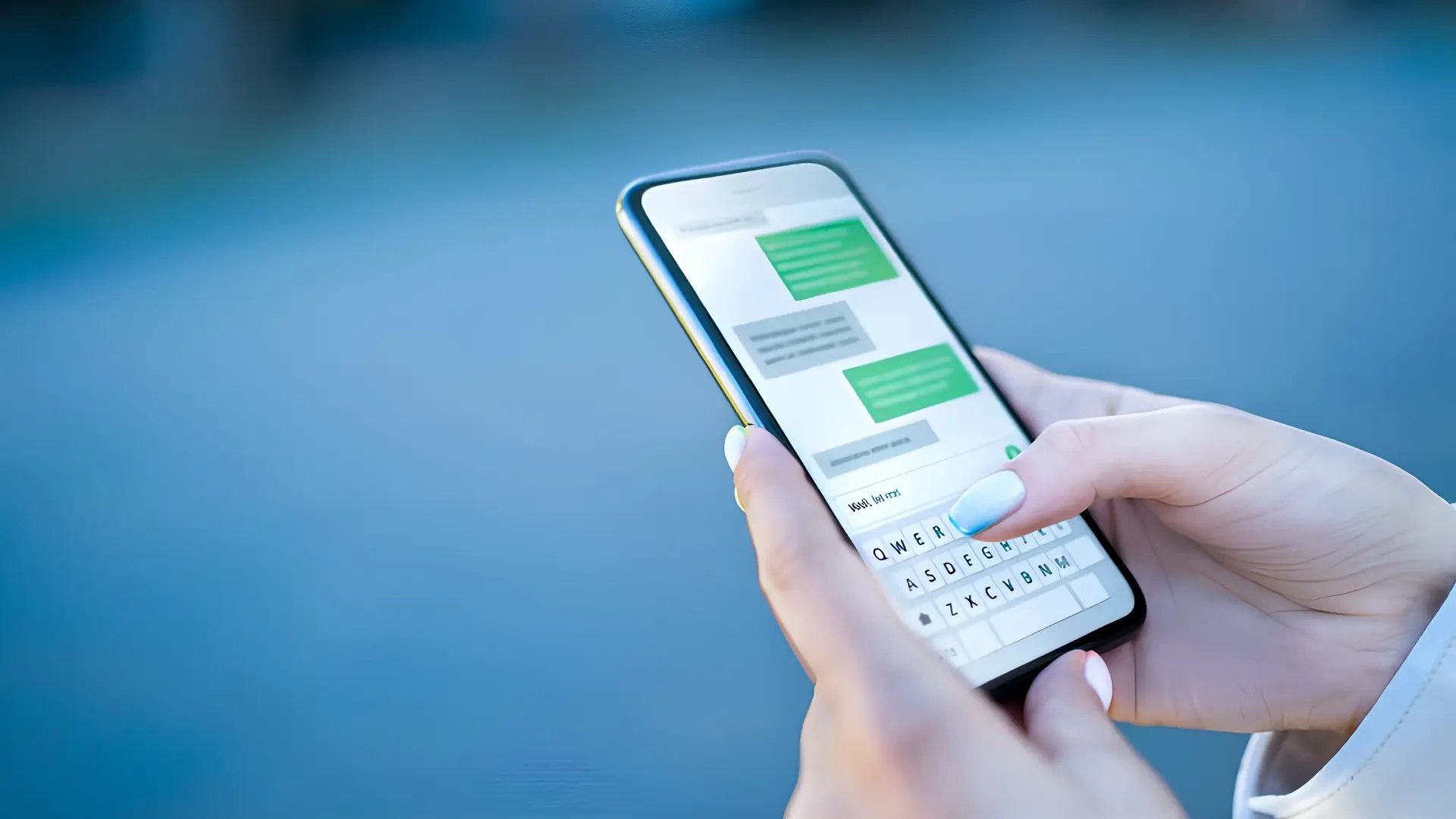 Female hands with light blue nail polish reading an SMS on her smartphone