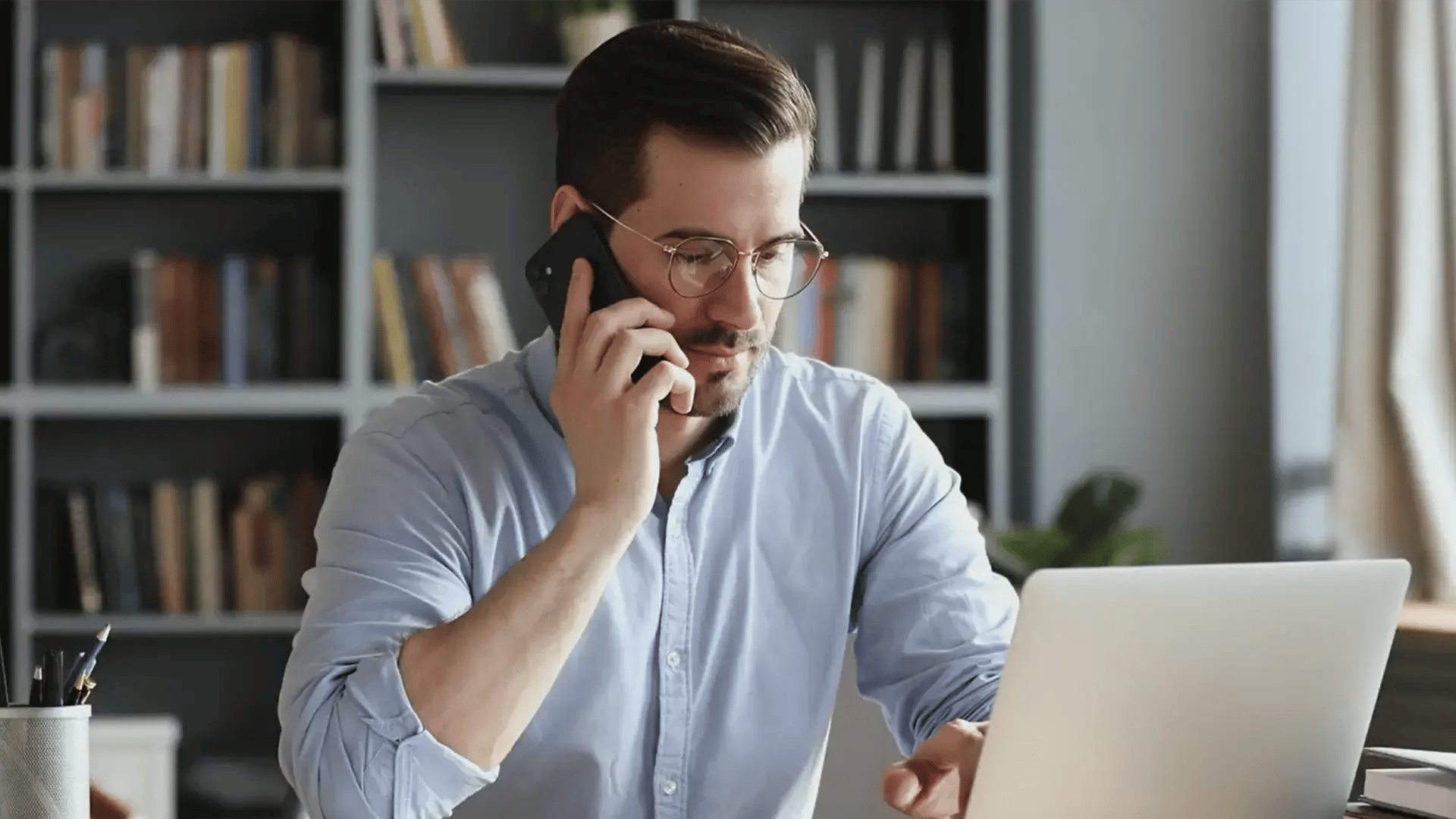 A man working on his laptop while taking a call on the mobile phone