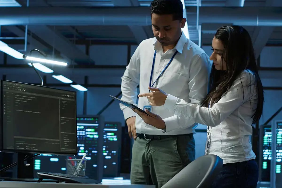 Two telecom engineers, a man and a woman, collaborates on network monitoring analysis