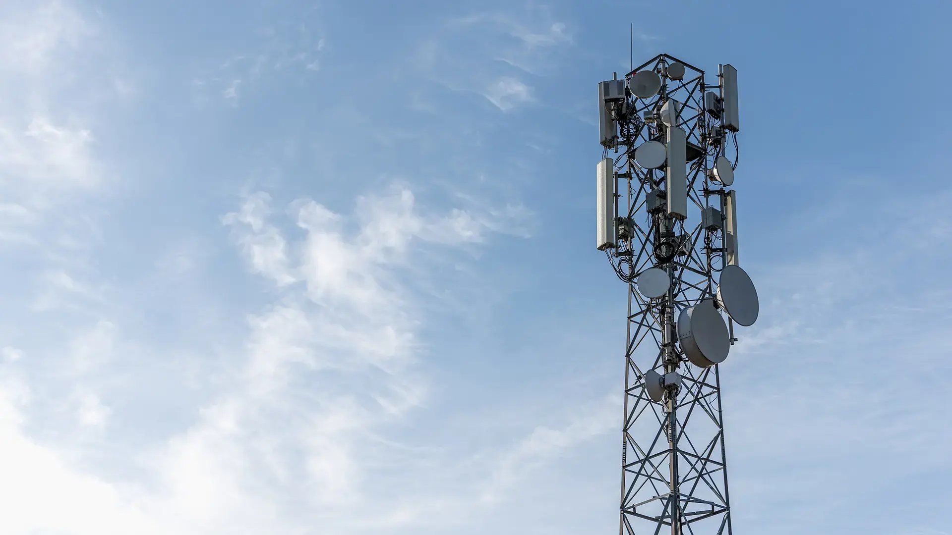 A telecom tower with base stations with a blue sky in the background