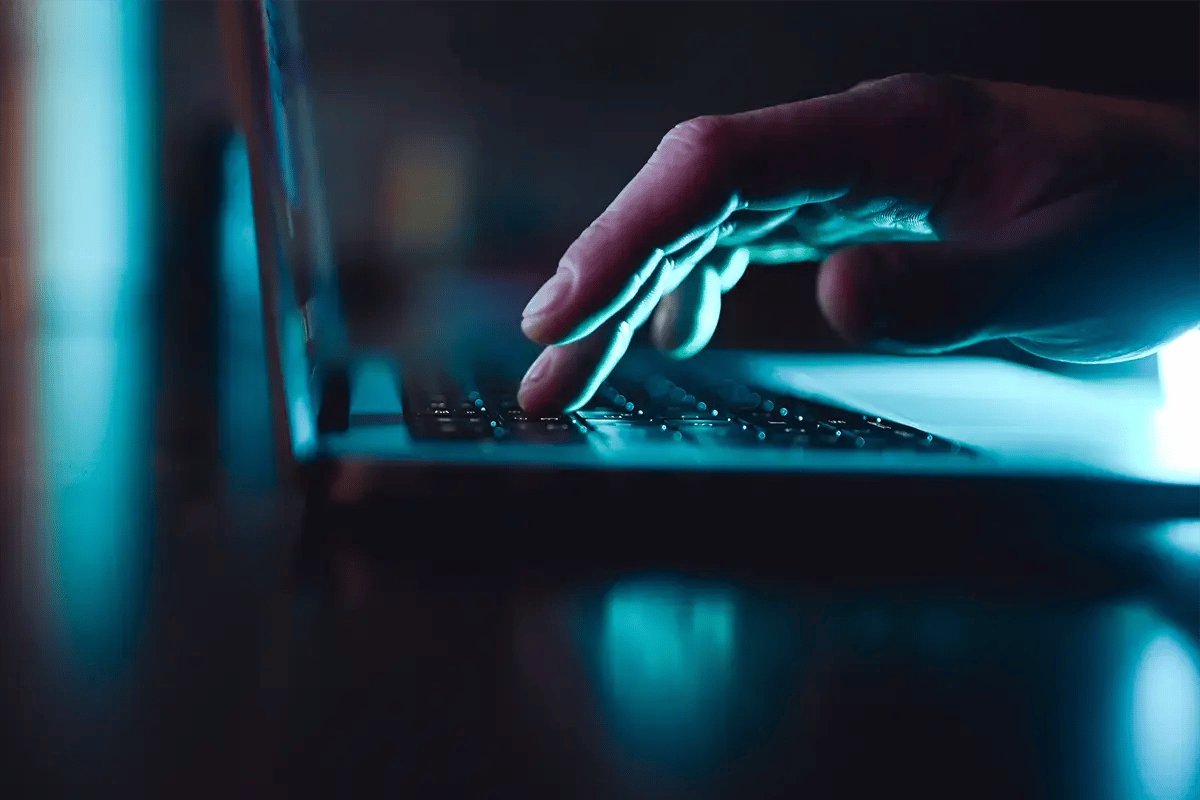 Dark image with one hand working on a laptop