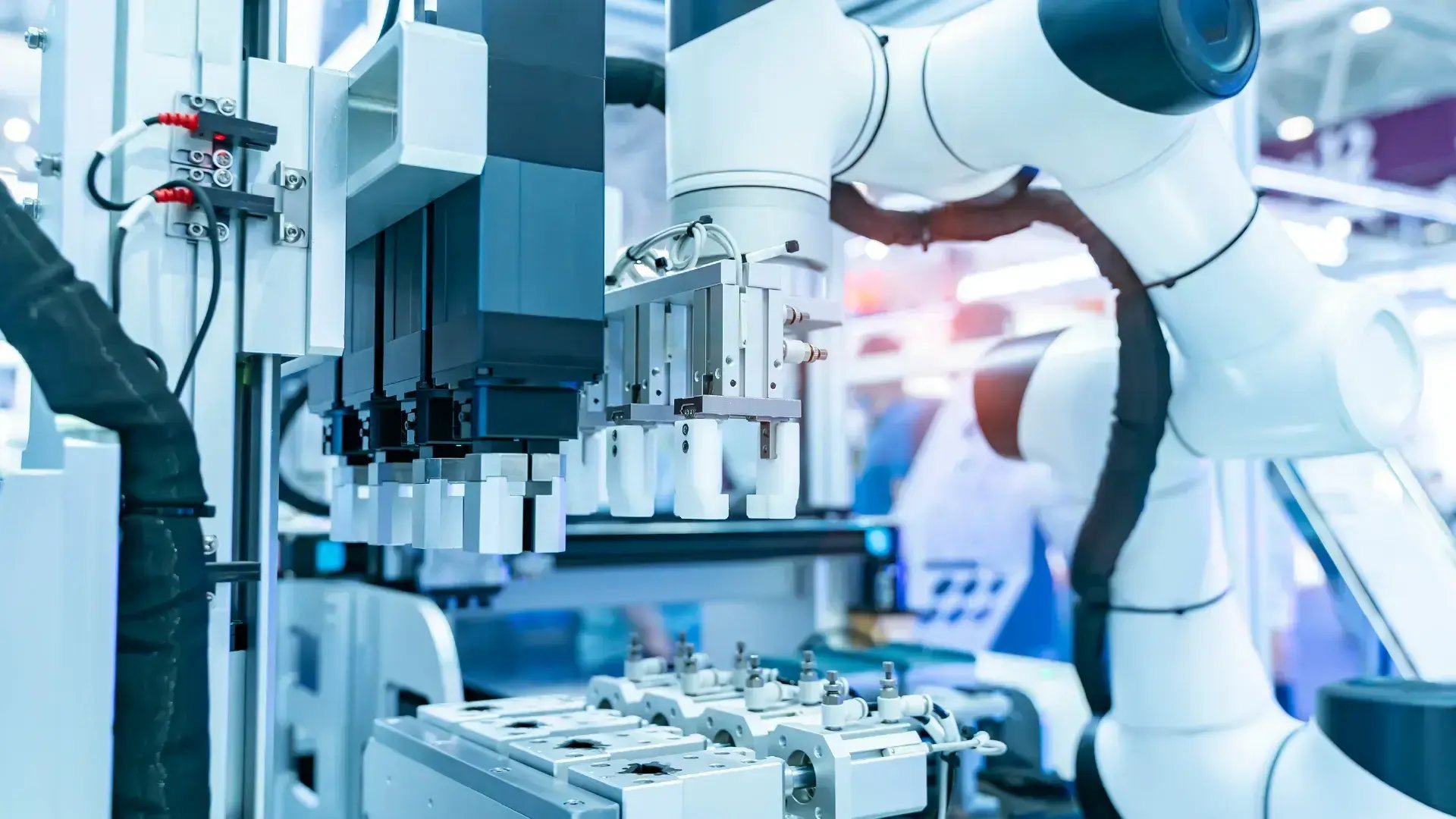 Industrial robotic arm with multiple grippers in a blurred high-tech setting, representing precision automation and advanced manufacturing technology.