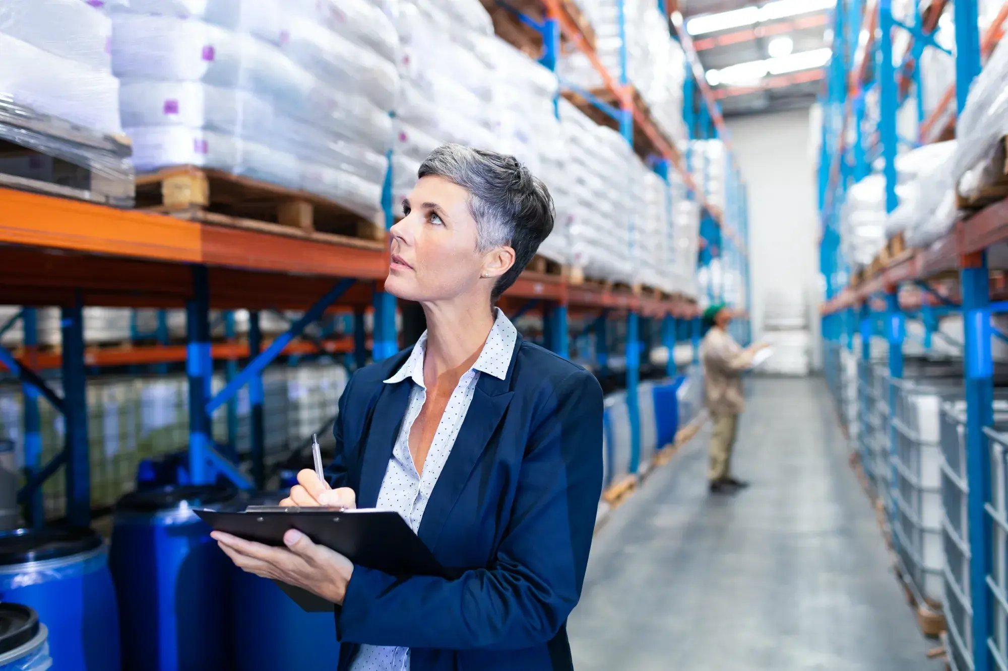 female-manager-checking-stocks-clipboard-warehouse