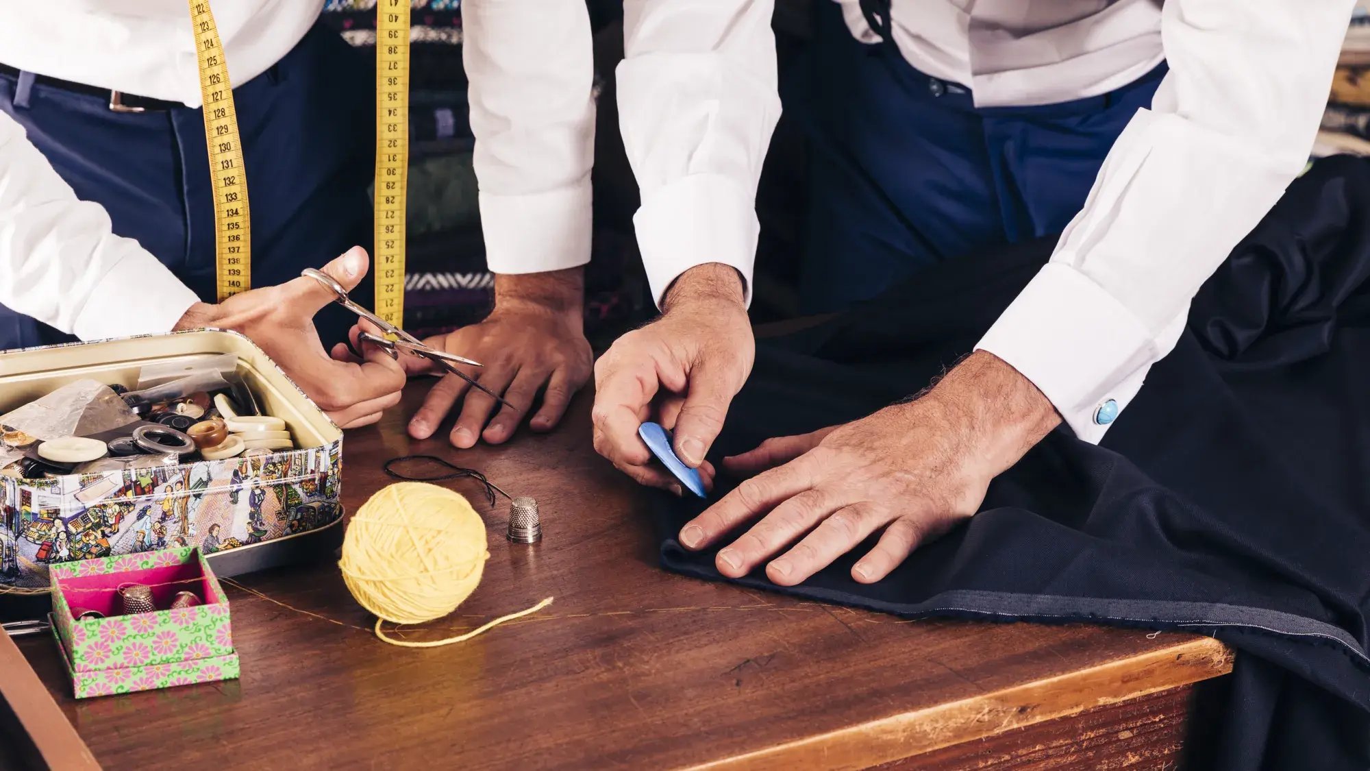 senior-male-tailor-marking-cloth-pattern-with-chalk-workshop