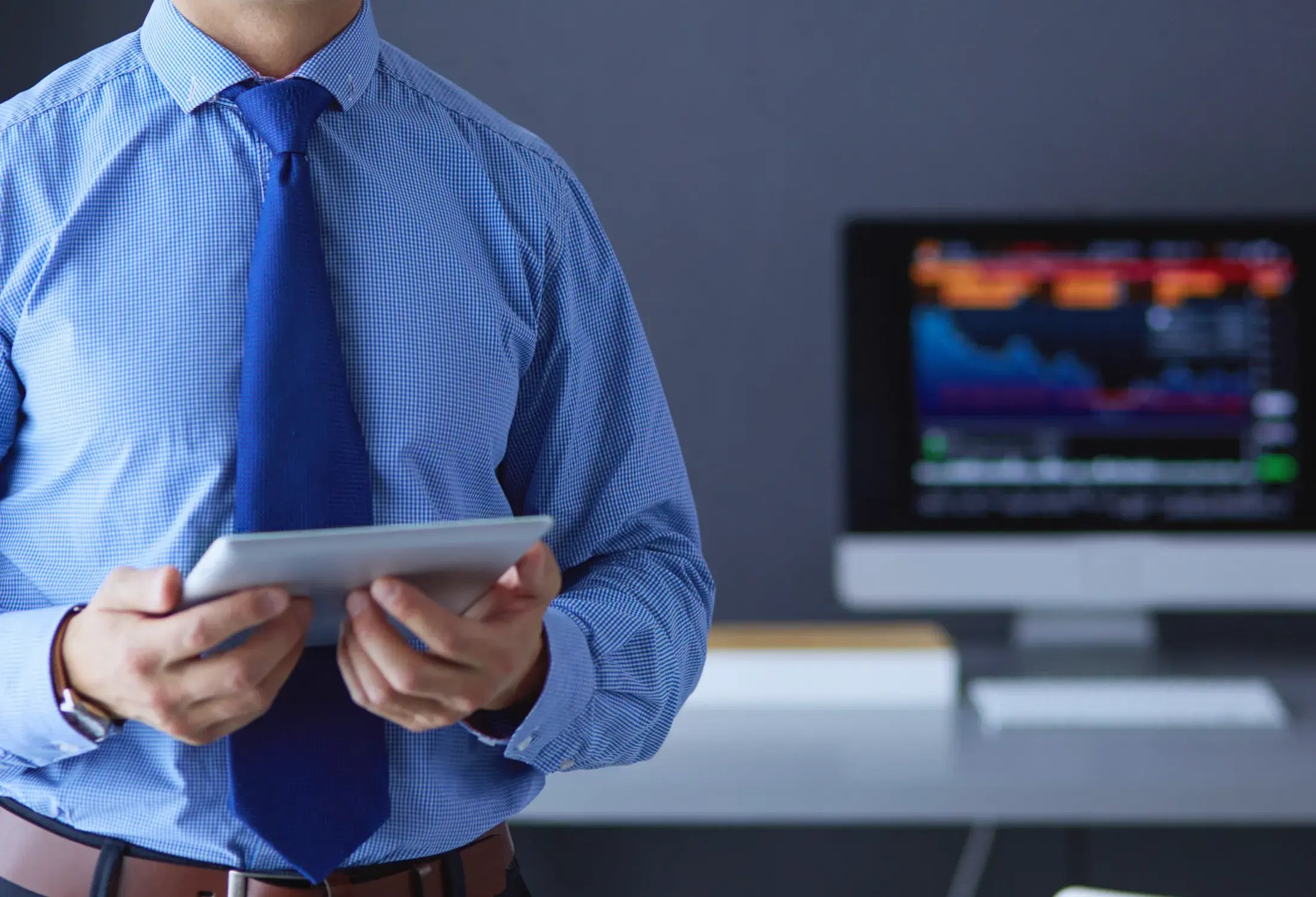 smiling-businessman-with-touchpad-standing-workplace-office